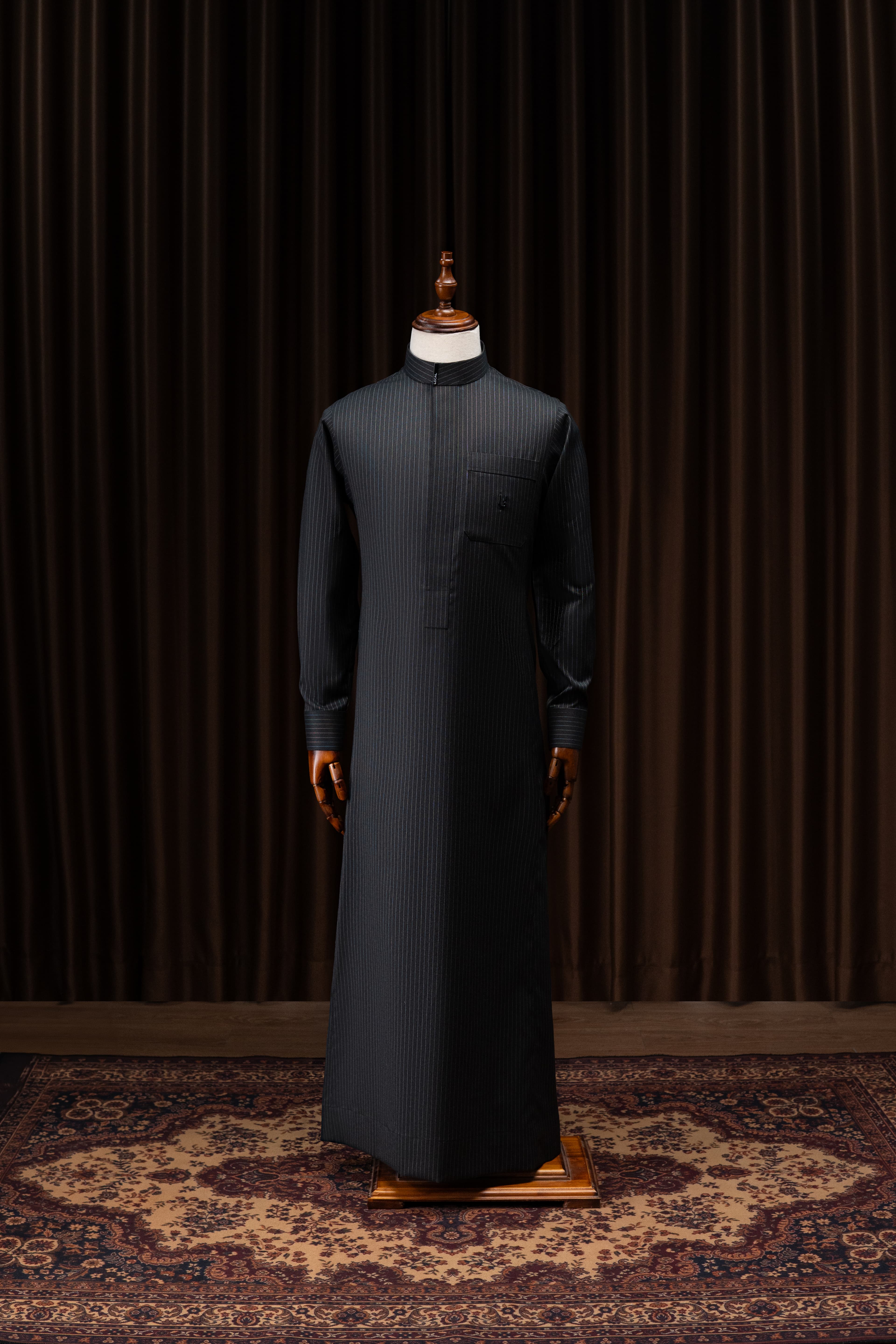 Bespoke black pinstripe thobe presented on a mannequin, editorial studio photography
